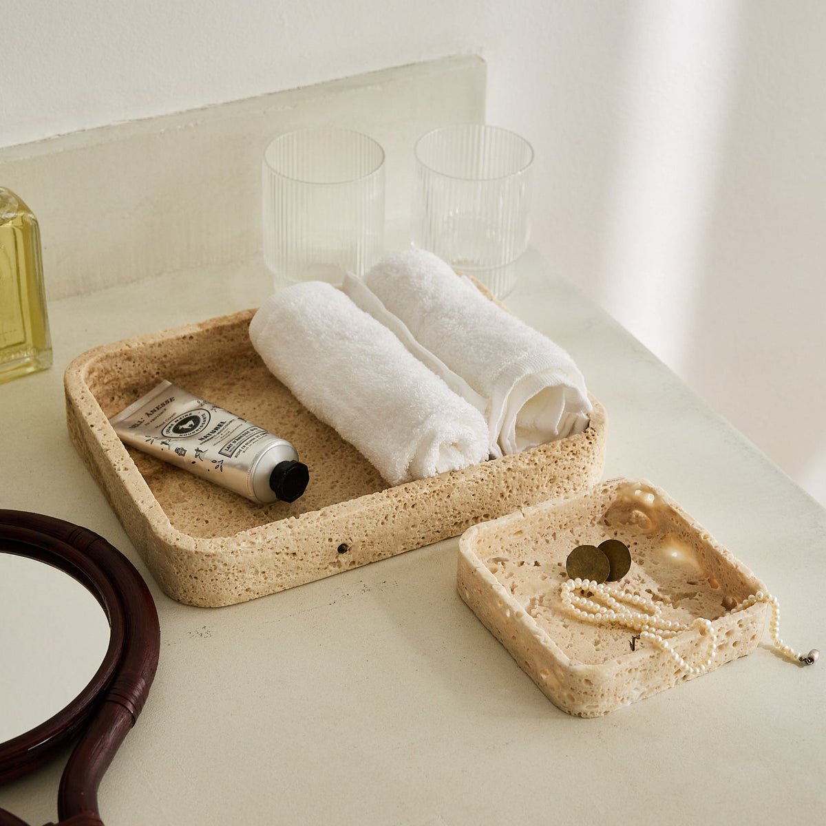 Handcrafted travertine tray with porous texture in soft beige tones as modern table decor